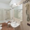 Bagno con vasca, lavabo, specchio e asciugacapelli a parete.