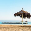 Spiaggia con sabbia dorata e due ombrelloni di paglia vicino al mare.