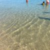 Acqua limpida al mare con alcune persone che nuotano vicino alla riva.