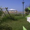 Prato con altalena e gazebo davanti al mare.