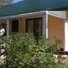 Bungalow giallo con piante verdi e fiori bianchi.