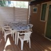Terrazza in legno con tavolo, sedie bianche e pareti a persiana.