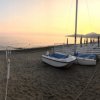 Spiaggia al tramonto con barche a vela sulla sabbia.