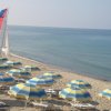 Ombrelloni e barca a vela su spiaggia sabbiosa.