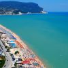 Spiaggia affollata con ombrelloni colorati e mare turchese.