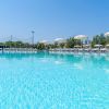 Ampia piscina con lettini e ombrelloni sotto un cielo blu.