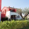 Casa rossa con giardino e alberi.