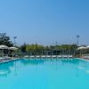 Piscina con lettini e ombrelloni sotto il cielo blu.