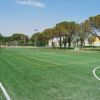 Campo sportivo recintato con porte e alberi sullo sfondo.