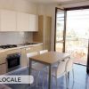 Cucina moderna con tavolo, sedie e porta finestra aperta.
