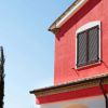 Parete di casa rossa con persiane scure.