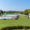 Piscina esterna con lettini su prato verde.