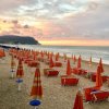 Spiaggia con ombrelloni arancioni al tramonto.