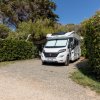 Camper parcheggiato tra siepi in un'area verde.