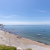 Spiaggia rocciosa con mare calmo all'orizzonte.