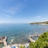 Spiaggia rocciosa con mare calmo e cielo sereno.