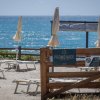 Spiaggia con lettini e ombrelloni chiusi, vista mare.