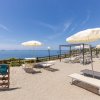 Spiaggia sabbiosa con ombrelloni bianchi e vista mare.