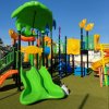Parco giochi colorato con scivoli verdi e arancioni.