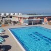 Ampia piscina con lettini e ombrelloni a righe.