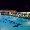 Piscina illuminata di notte, circondata da lettini.