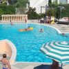Piscina all'aperto con persone che nuotano e un ombrellone a strisce.