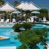 Piscina con piante e lettini bianchi, vista mare.