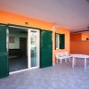 Terrazza con tavolo e panca bianchi davanti a porte-finestra verdi.