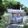 Casa bianca con tetto curvo e giardino ricco di vegetazione.
