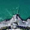 Veduta aerea di una struttura con reti su una costa rocciosa.