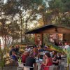 Gruppo di persone sedute all'aperto in un bar tra gli alberi.