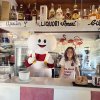 Barista e mascotte in un bar con bottiglie di alcolici.