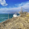 Struttura di legno sul mare con onde che si infrangono sulle rocce.