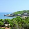 Una costa verdeggiante con case bianche e il mare all'orizzonte.