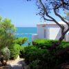 Casa bianca vicino al mare, circondata da alberi verdi.