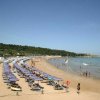 Spiaggia affollata con ombrelloni colorati e bagnanti in mare.