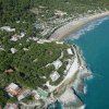 Vista aerea di una spiaggia con ombrelloni e vegetazione circostante.