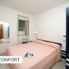Camera da letto con letto matrimoniale, coperta rosa, finestra aperta e specchio a parete.