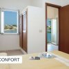 Stanza con letto matrimoniale, coperta gialla, finestra vista mare e porta marrone.
