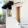 Entrata di una casa bianca con tetto in legno circondata da alberi.