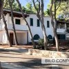 Edificio bianco a due piani immerso in una pineta.