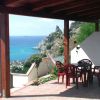 Terrazza con sedie e vista mare e scogli.