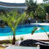 Piscina esterna con palme e persone in lontananza.