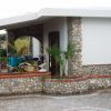 Ingresso di casa in pietra con piante e sedie.