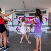 Bambini che ballano su un palco in una sala con decorazioni colorate.