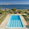 Piscina con lettini e ombrelloni su un prato, vista mare.