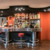 Bar moderno con sgabelli rossi e mensole piene di bottiglie.