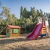 Casetta di legno e scivolo colorato in un parco giochi all'aperto.