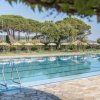 Una piscina all'aperto con lettini e ombrelloni, circondata da alberi.