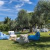 Area esterna con poltrone a sacco su un prato, circondate da alberi e allestimenti per eventi.